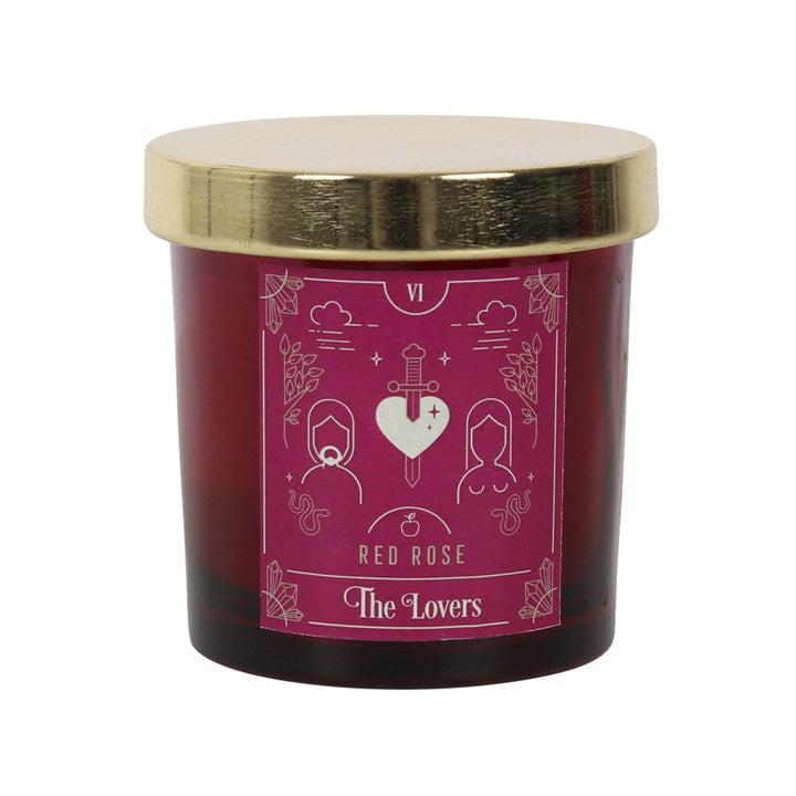A red rose coloured candle with a tarot card design on the label, accompanied by a gold lid.