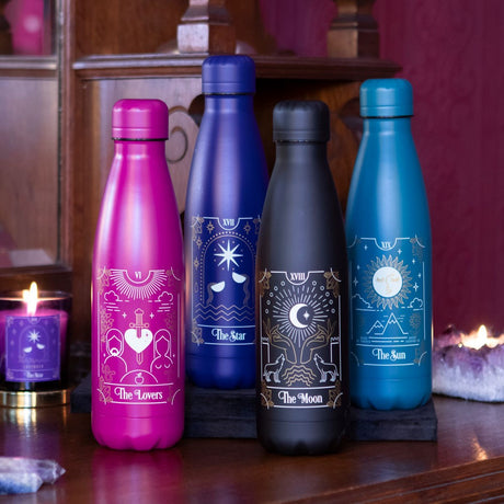A collection of metal water bottles in pink, blue, and black colours, each featuring a different tarot card illustration.