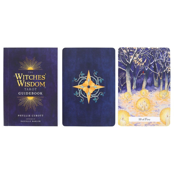 A blue guidebook for "The Witches' Wisdom" Tarot cards lays next to two oracle cards on a white surface. The first card is blue with a yellow flower in the centre, the second is "10 of Fire" and is an abstract, blue woodland image with lit candles on the floor.