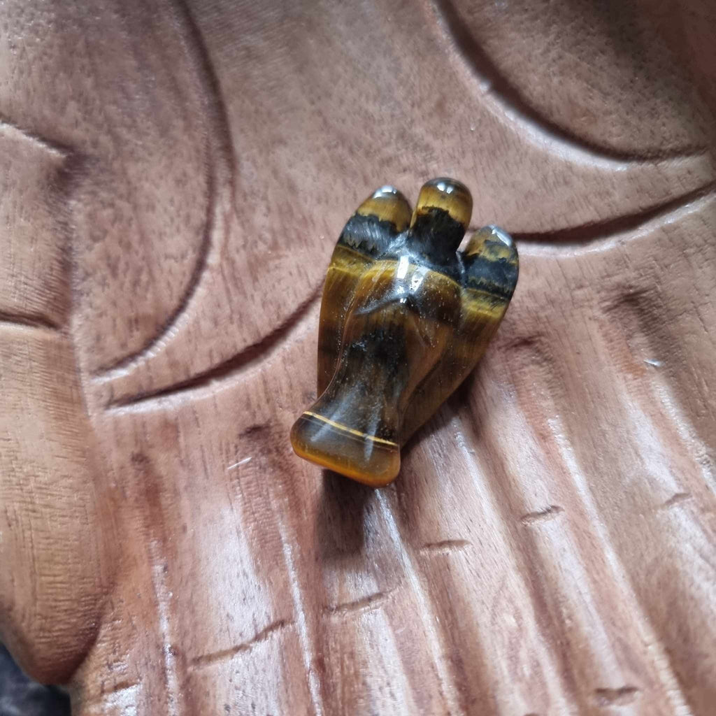 A brown and gold crystal angel on a wooden backdrop 