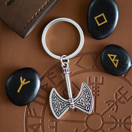 Keychain with axe design on a brown surface with stones featuring rune symbols