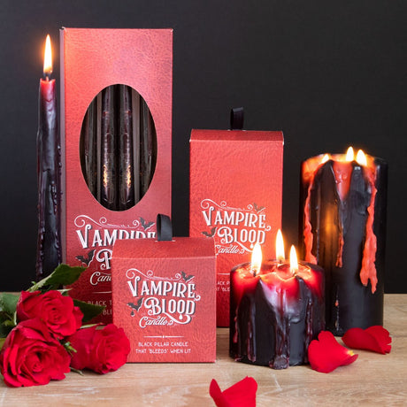 A selection of pillar and taper shaped red and black wax candles named Vampire Blood, with melted wax dripping down the side.
