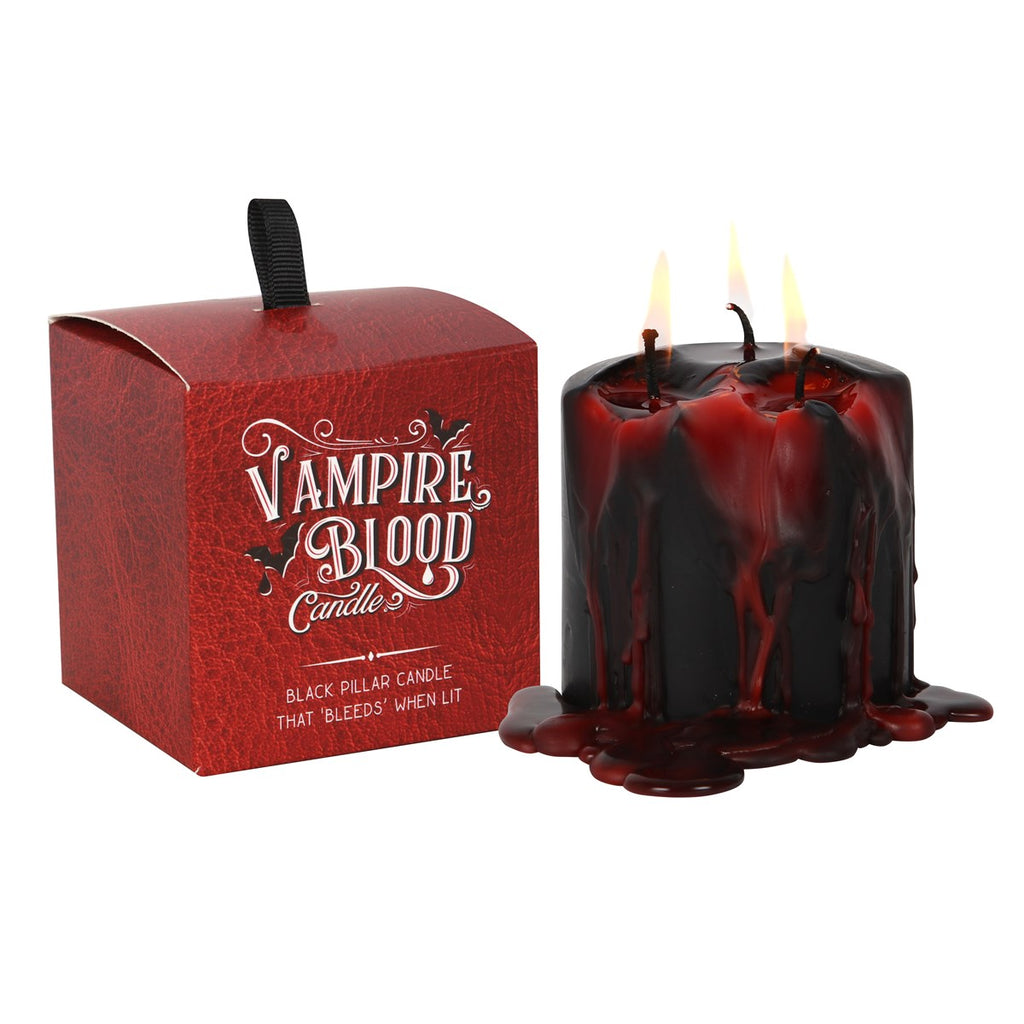 A pillar-shaped red and black wax candle with three wicks, named Vampire Blood, with melted wax dripping down the side.