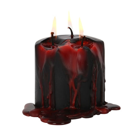 A pillar-shaped red wax candle with three wicks, named Vampire Tears, with melted wax dripping down the side.