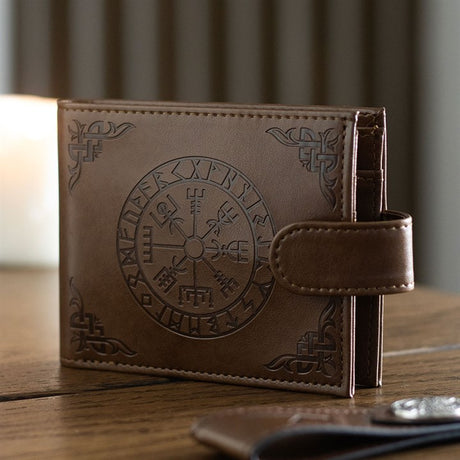 Brown leather wallet with embossed Viking compass design on a wooden surface