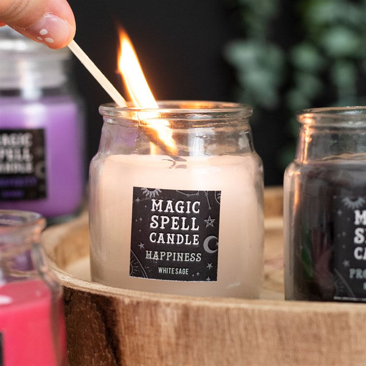 A small lit white Magic Spell Candles with a label that states it is for "Happiness" and is White Sage