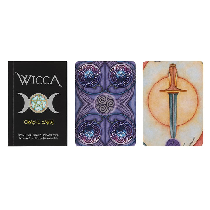 A guide book for "Wicca" oracle cards next to two oracle cards. One if mostly purples with intricate swirling patterns in four corners and the middle. The second is of a dagger.