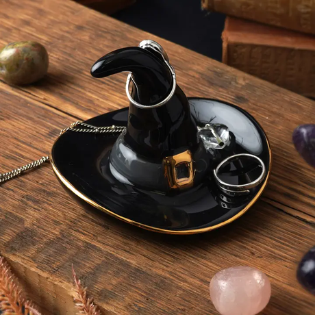 Black witch hat ring holder on a wooden surface with decorative elements.