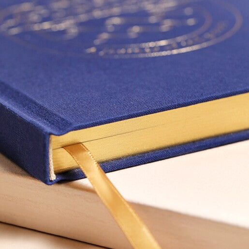 A navy blue journal with a gold detail on the cover, with a gold page edge.