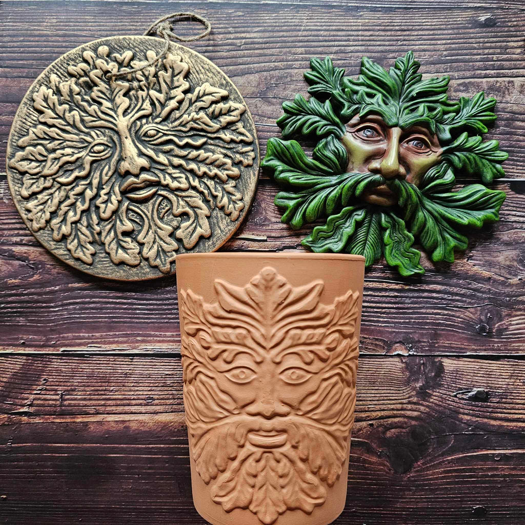 Three green man themed things; two plaques and a plant pot
