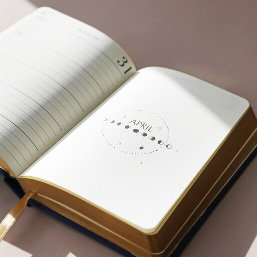 An open navy blue journal featuring moon phases 