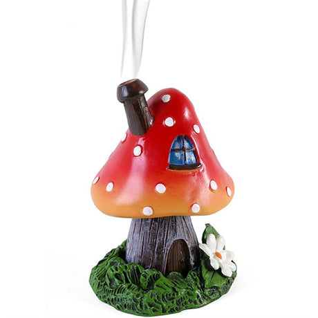 A red and orange toadstool-shaped incense burner with a house and chimney design, on a green base, intended for burning incense cones.