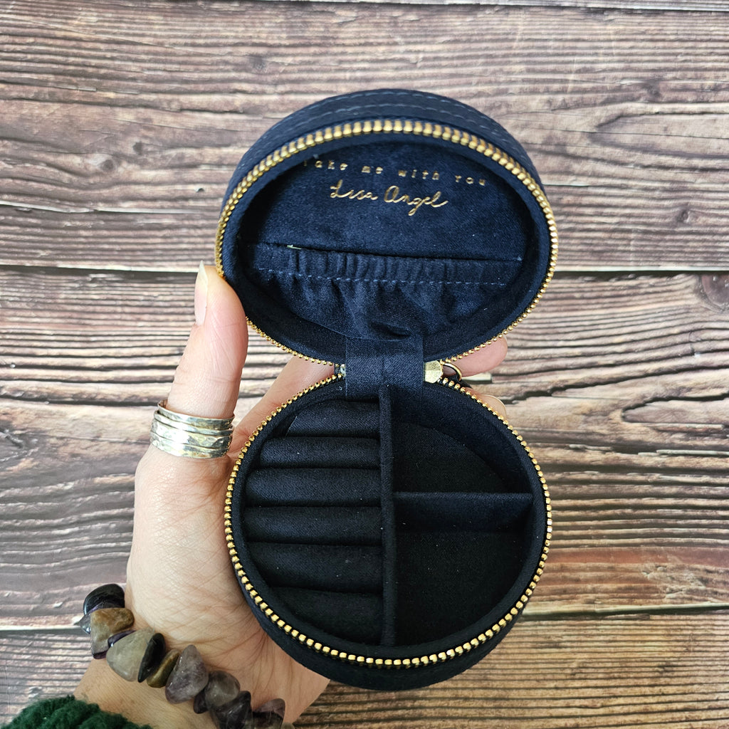 A person holding an open navy blue round jewellery case.