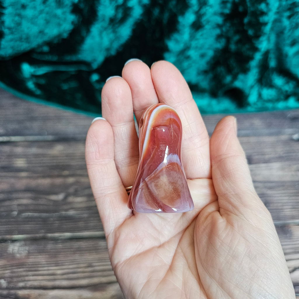 A Carnelian carved crystal ghost held in a person's hand