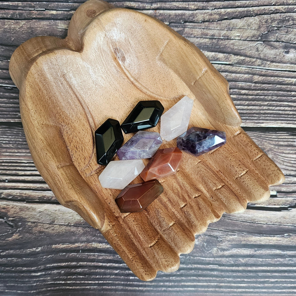 Several crystals shaped as coffins are laid in a pair of wooden hands
