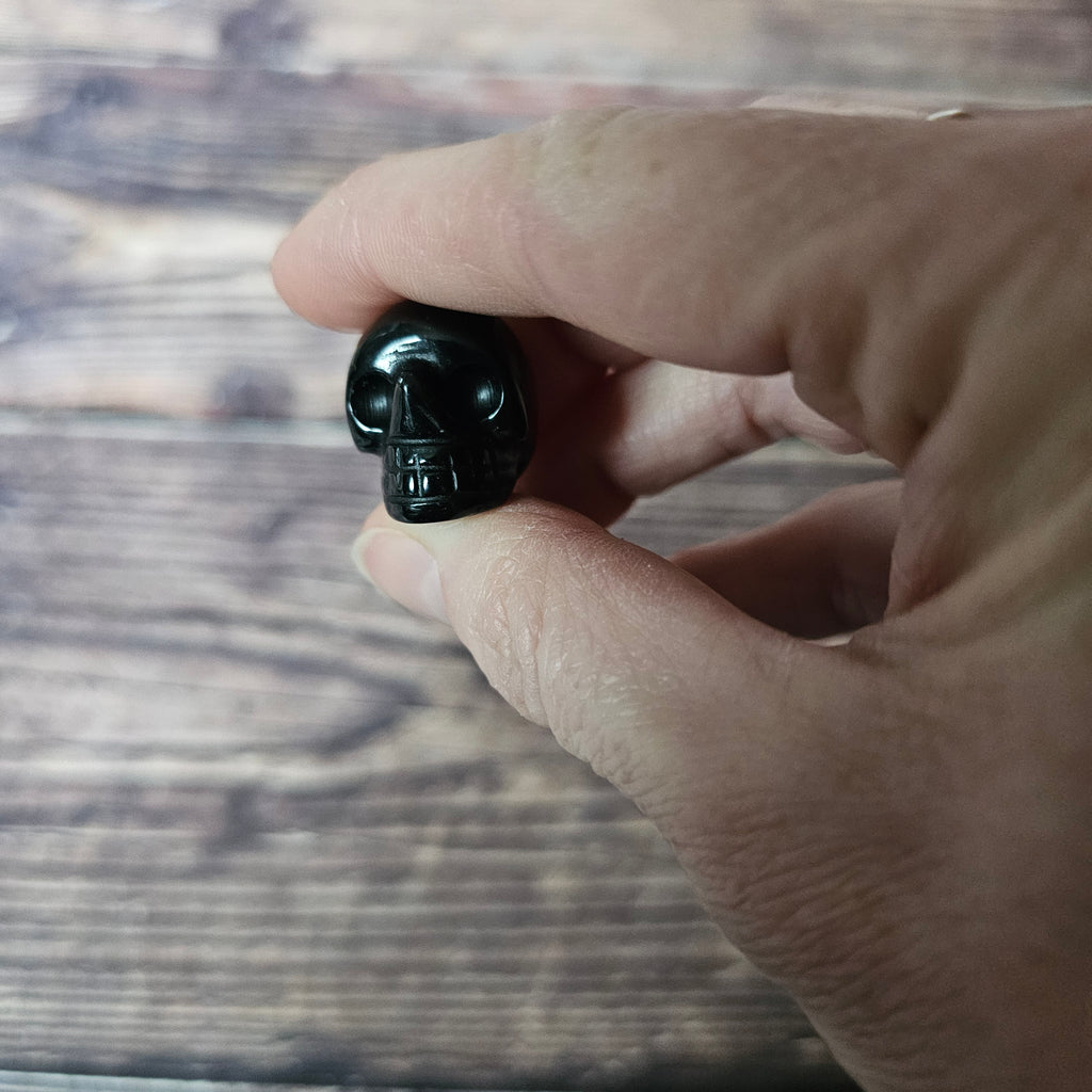 A small carved black crystal skull held in a hand