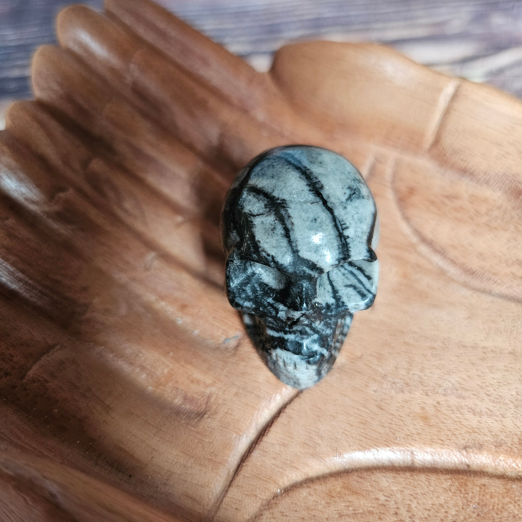 A carved crystal black and grey skull held in a hand