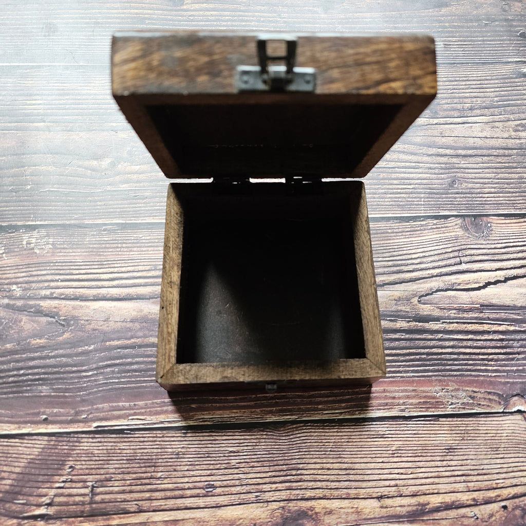 An open, empty wooden square box, placed on a wooden surface.