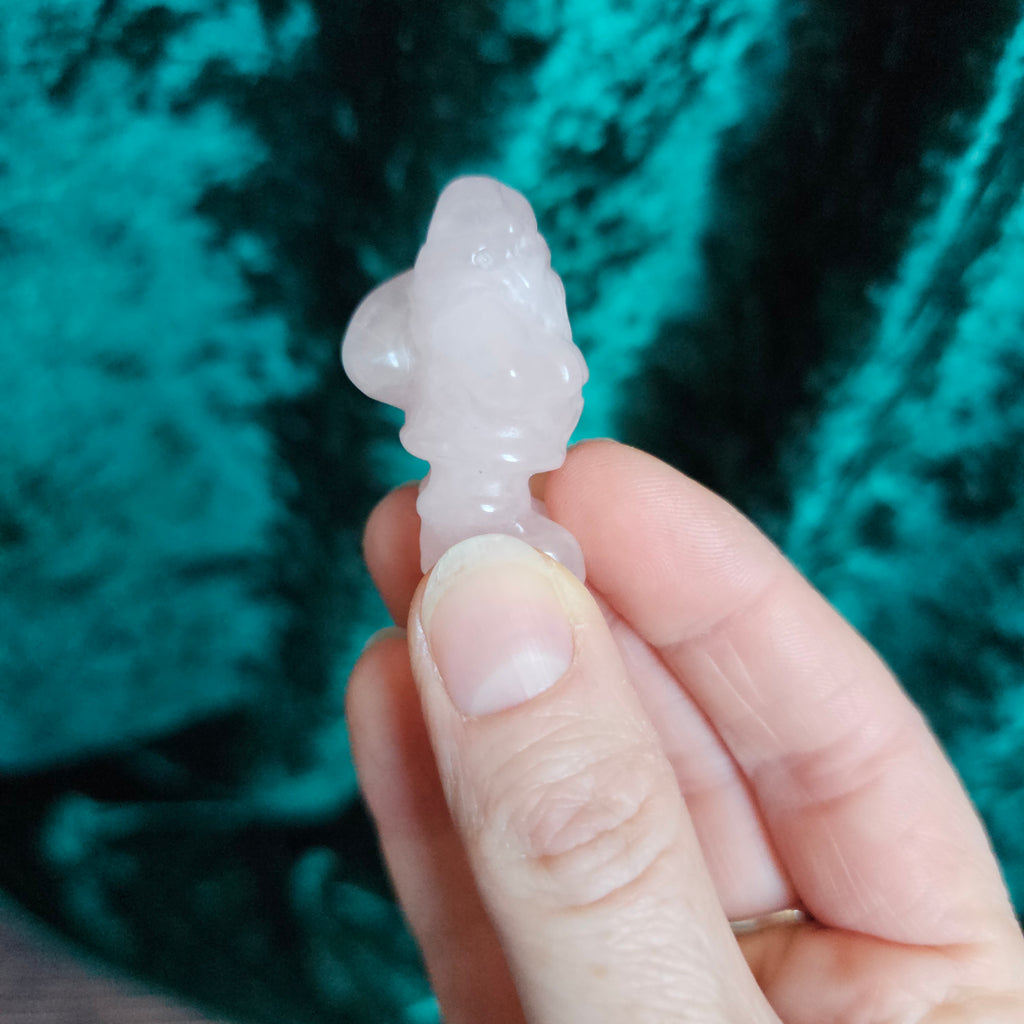 A carved pink crystal Santa figure held in a person's hand.