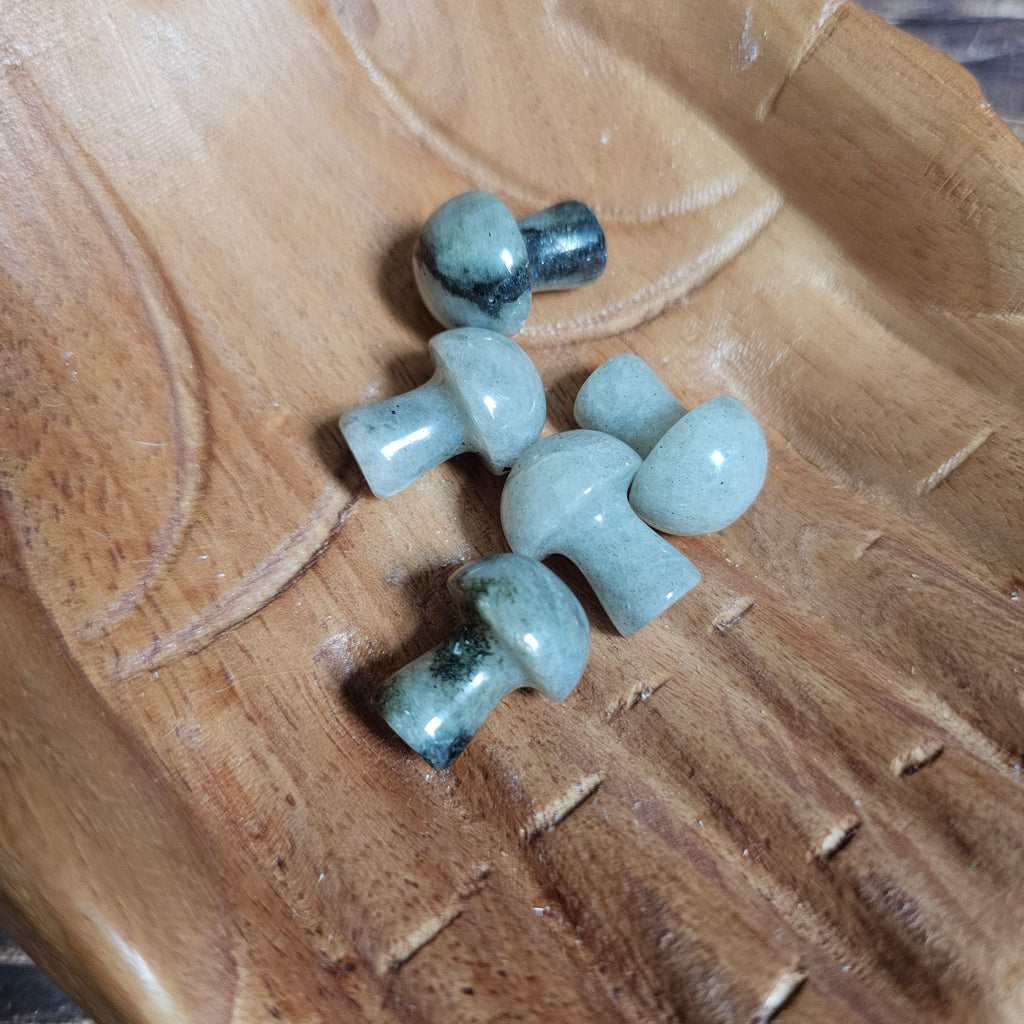 Five miniature crystal mushrooms placed on a wooden surface.