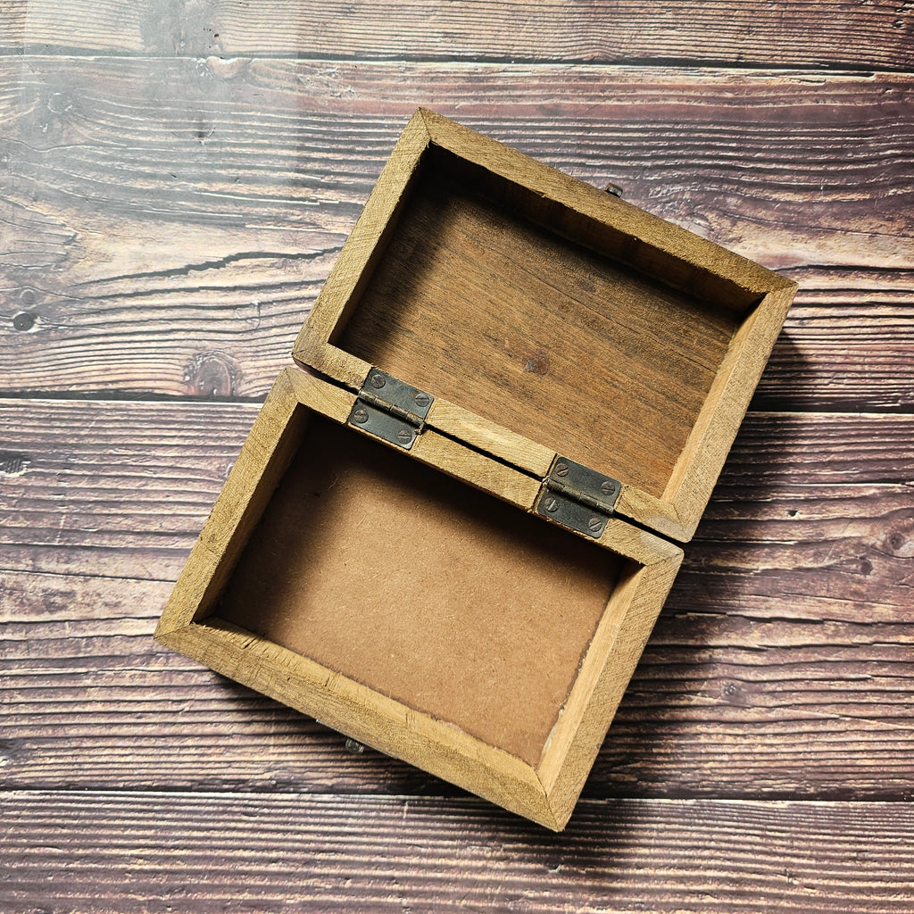 An open, empty wooden box, placed on a wooden surface.