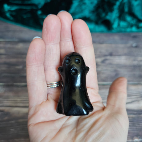A Black Obsidian carved crystal ghost held in a person's hand