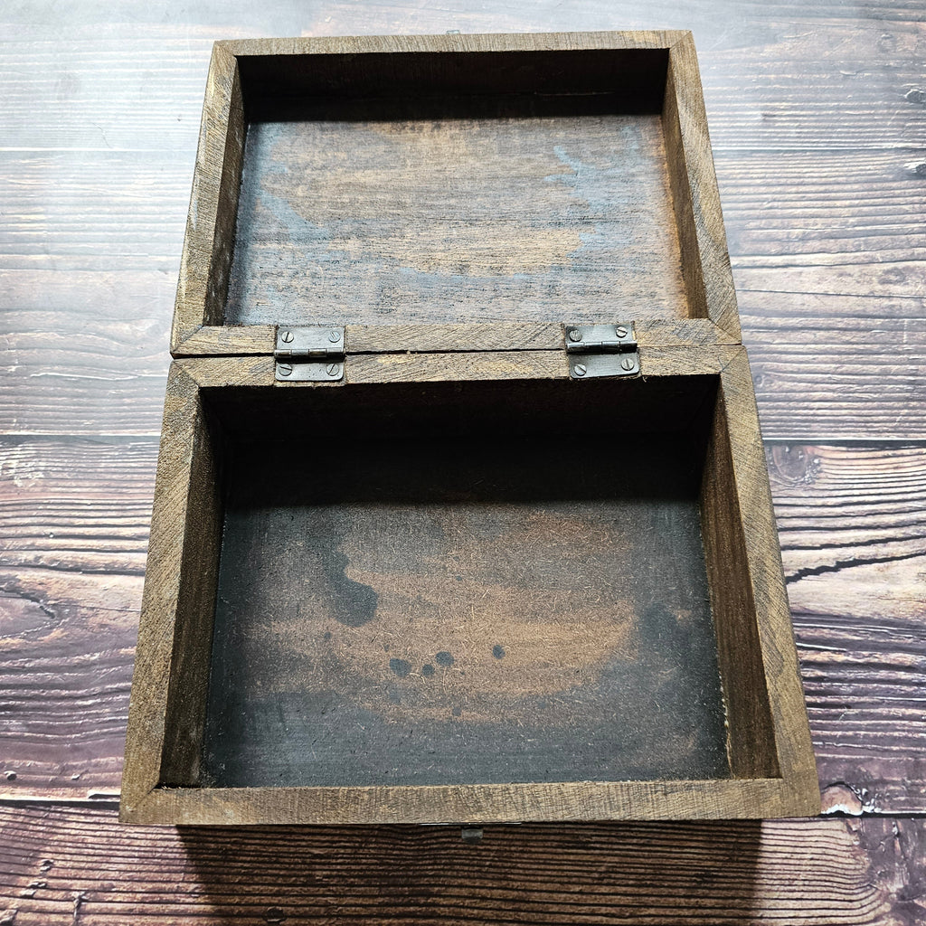 An open, empty wooden box, placed on a wooden surface.