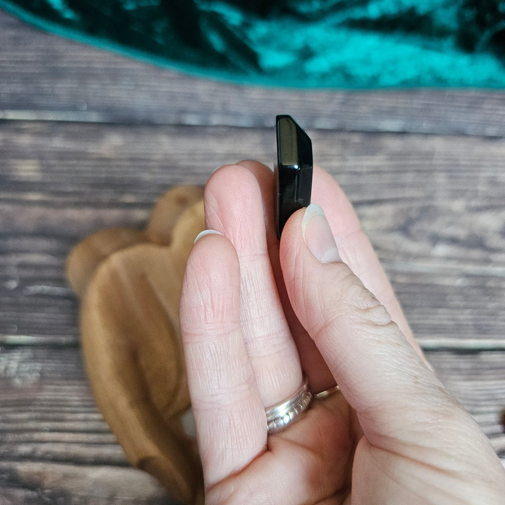 A Black Obsidian crystal coffin is being held in someone's hand
