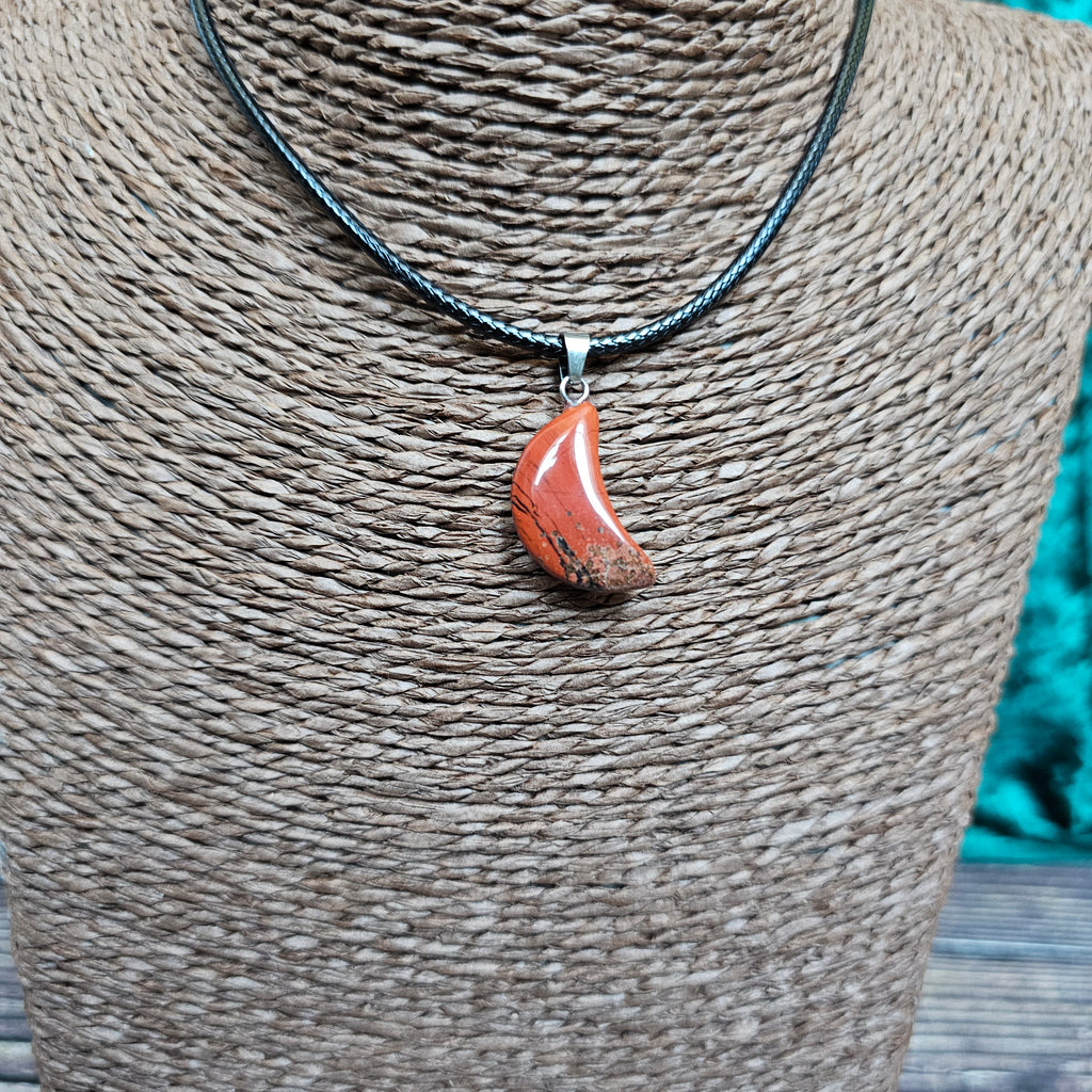 A crescent moon shaped crystal pendant on a black cord displayed on a mannequin 