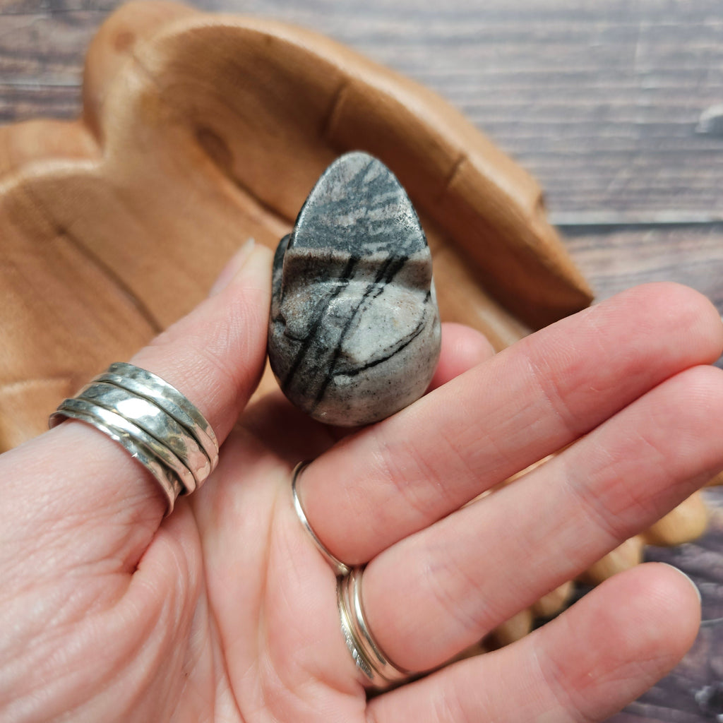 A carved crystal black and grey skull held in a hand