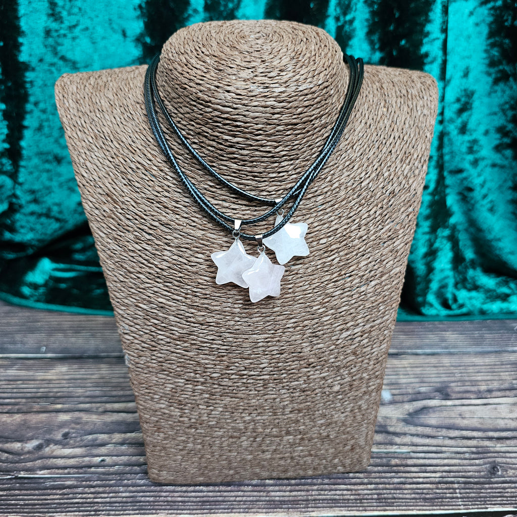 Three star-shaped crystal pendants in displayed on a brown mannequin, with a black cord.