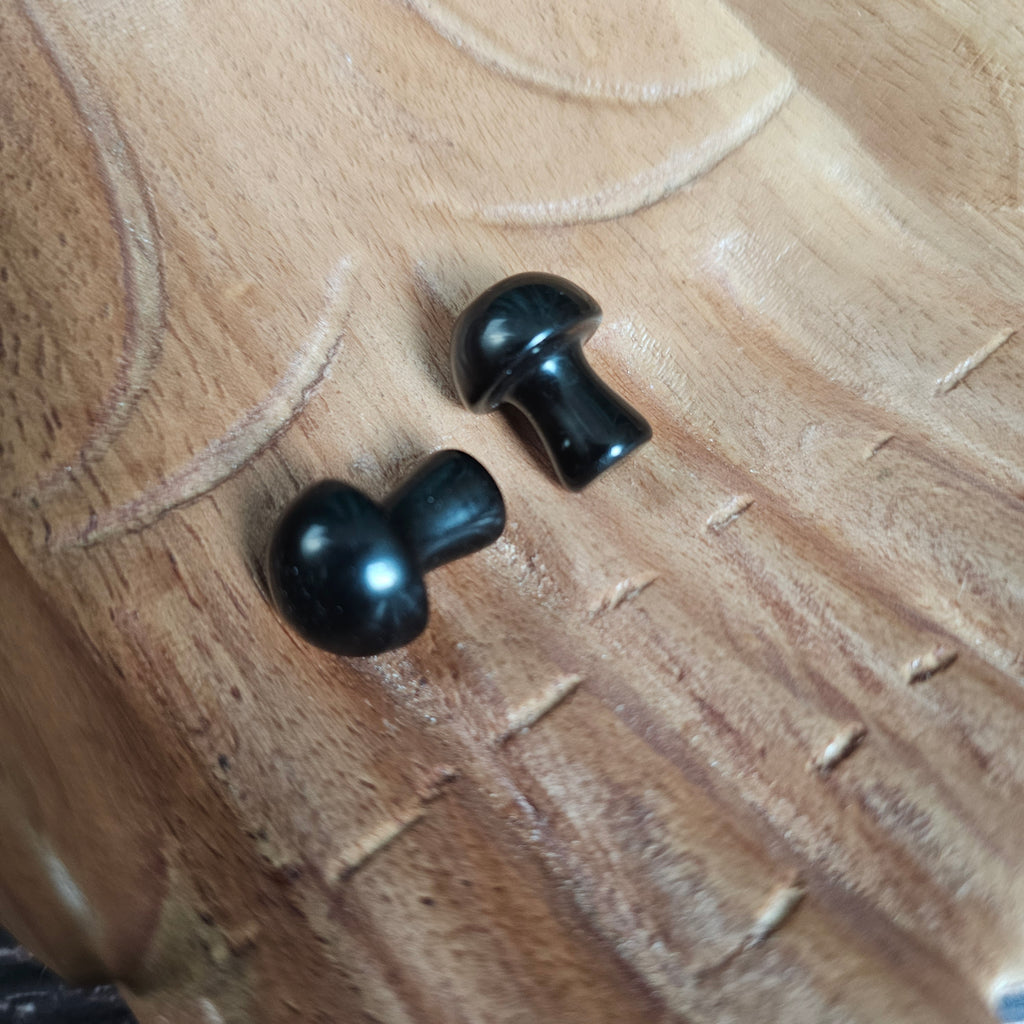 Two miniature crystal mushrooms placed on a wooden surface.