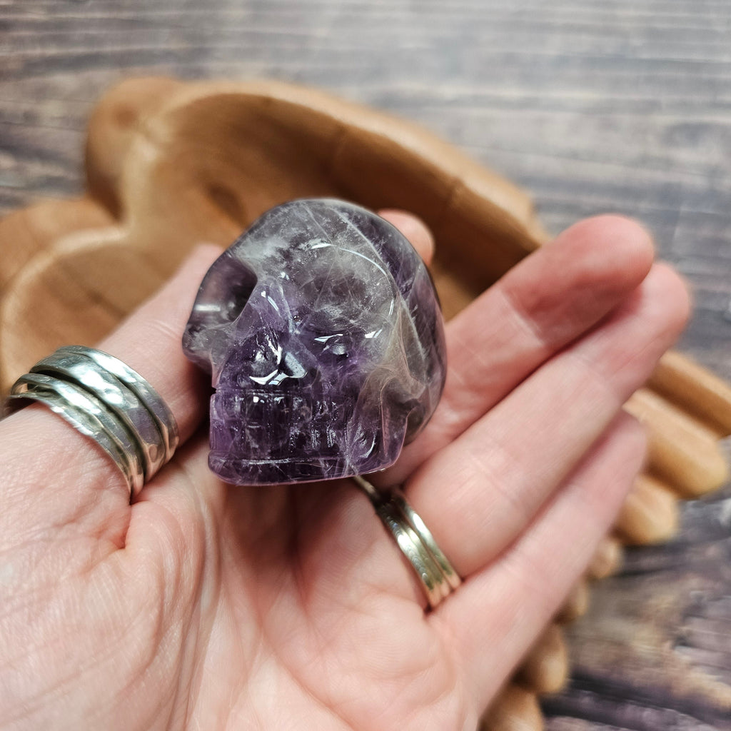 A carved Amethyst crystal skull held in a hand