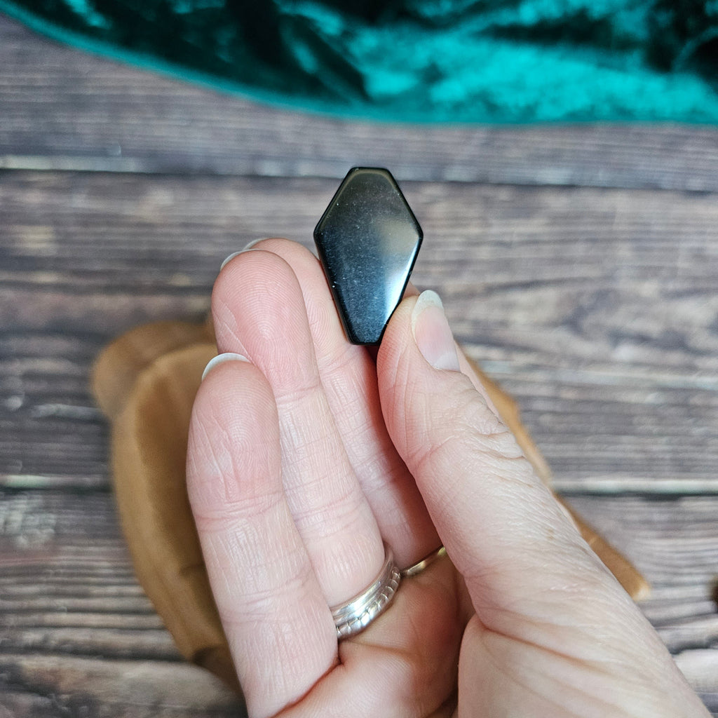 A Black Obsidian crystal coffin is being held in someone's hand
