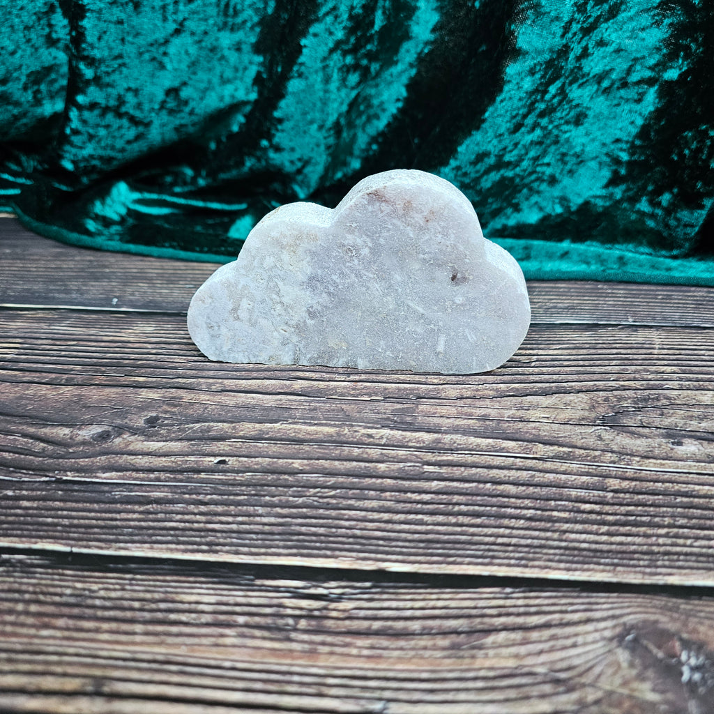 A carved Pink Amethyst crystal shaped as a stood on a wooden background