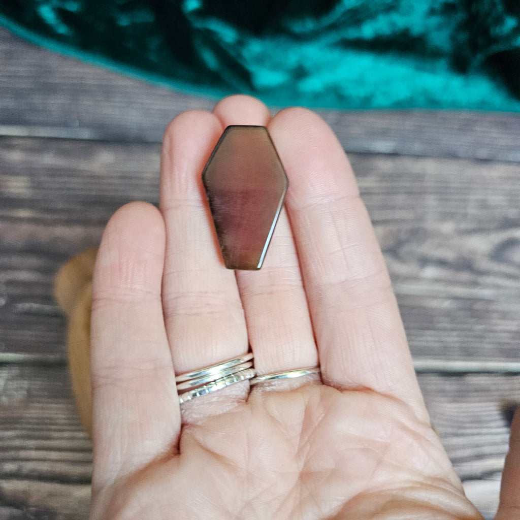 A Carnelian crystal coffin is being held in someone's hand