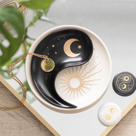 Two ceramic trinket dishes with a stacked yin yang and sun/moon design, displayed against a white background with a gold necklace.