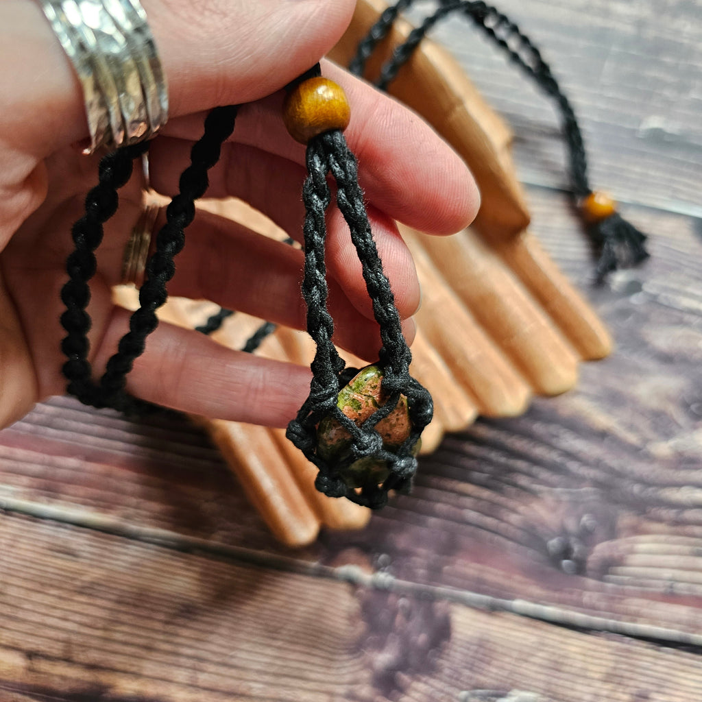 A black-coloured crystal cord necklace with an example crystal inside showing how it opens