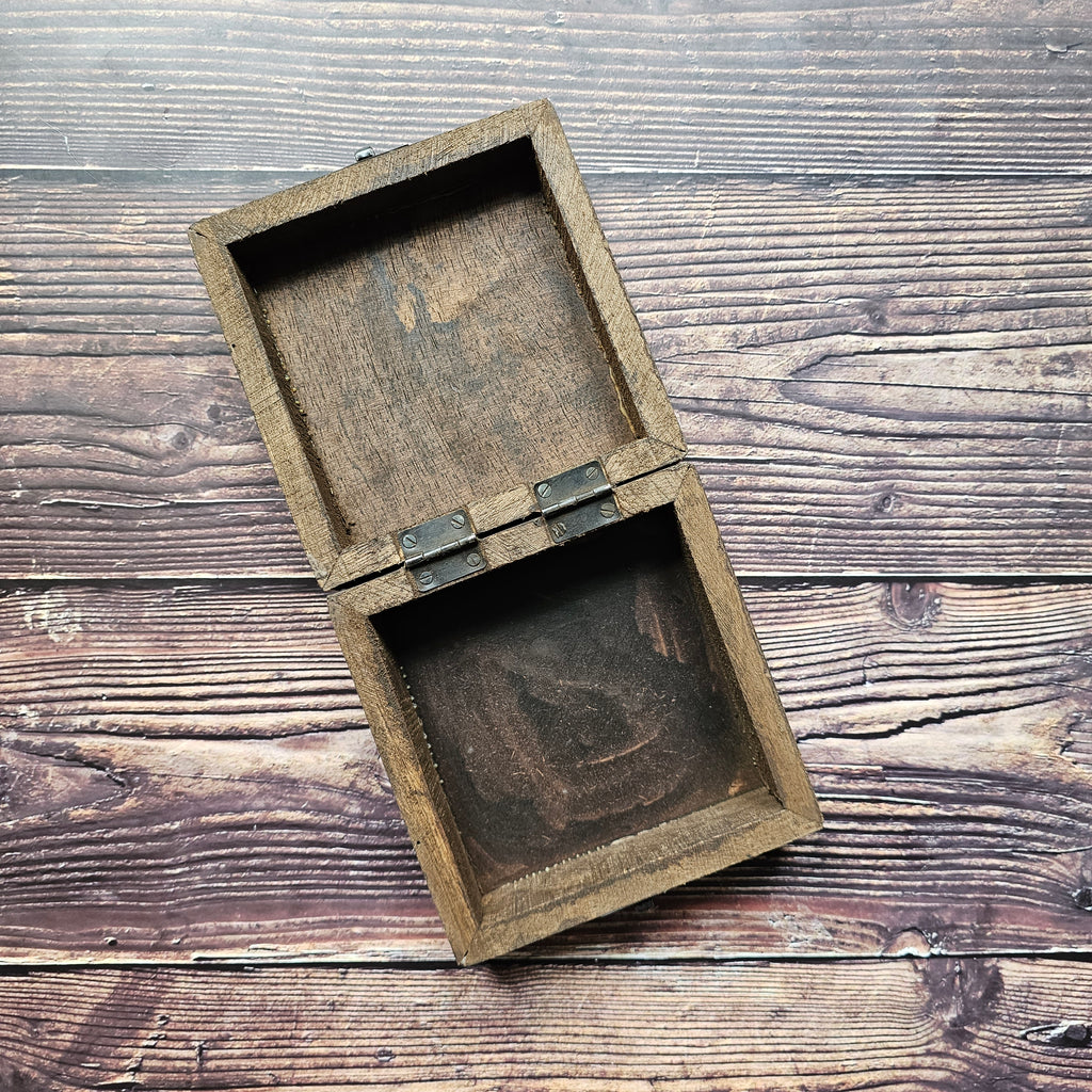 A square, empty wooden box with, placed on a wooden surface.