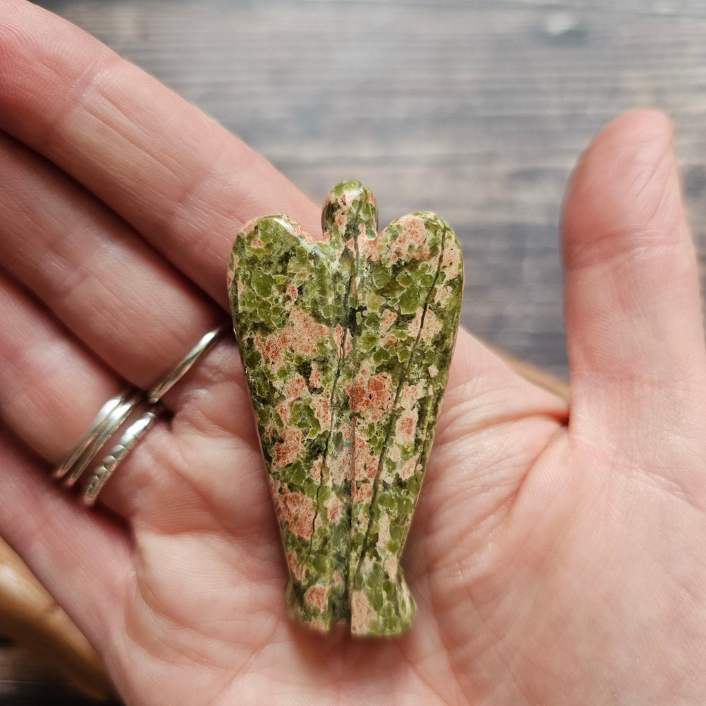 A carved crystal angel figurine placed held in a hand