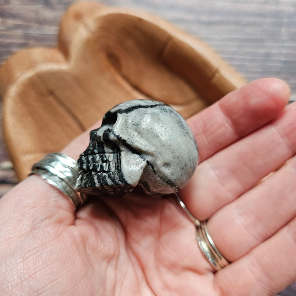 A carved crystal black and grey skull held in a hand