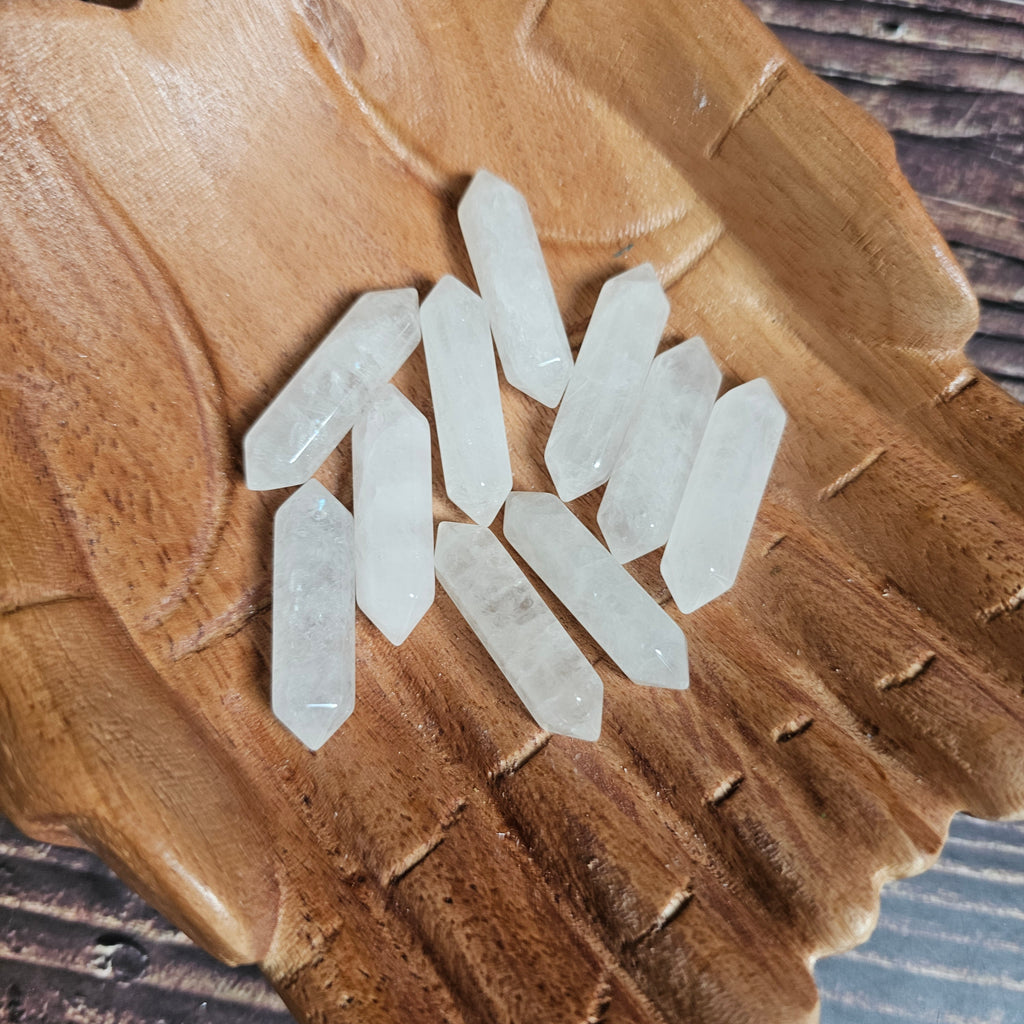 Small clear quartz double pointed crystals held in wooden carved hands