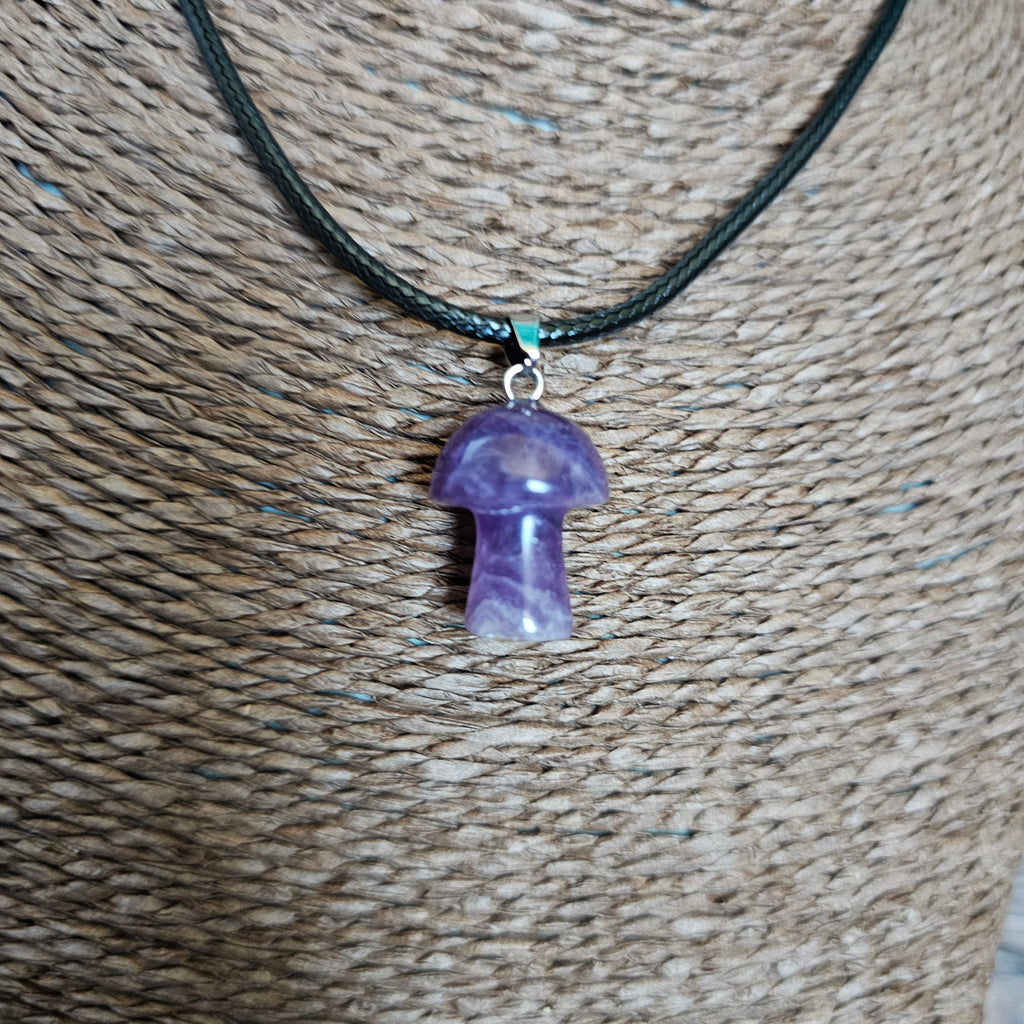 A mushroom-shaped crystal pendant attached to black cord, displayed on a mannequin. 