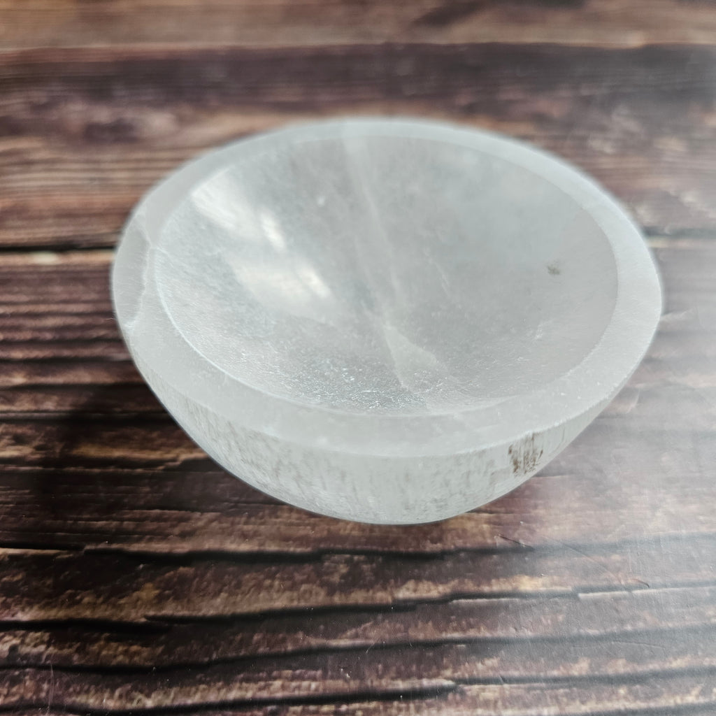 A white selenite bowl on a wooden surface
