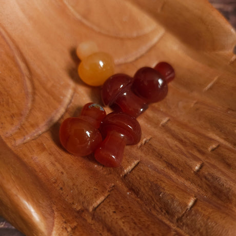 Five miniature crystal mushrooms placed on a wooden surface.