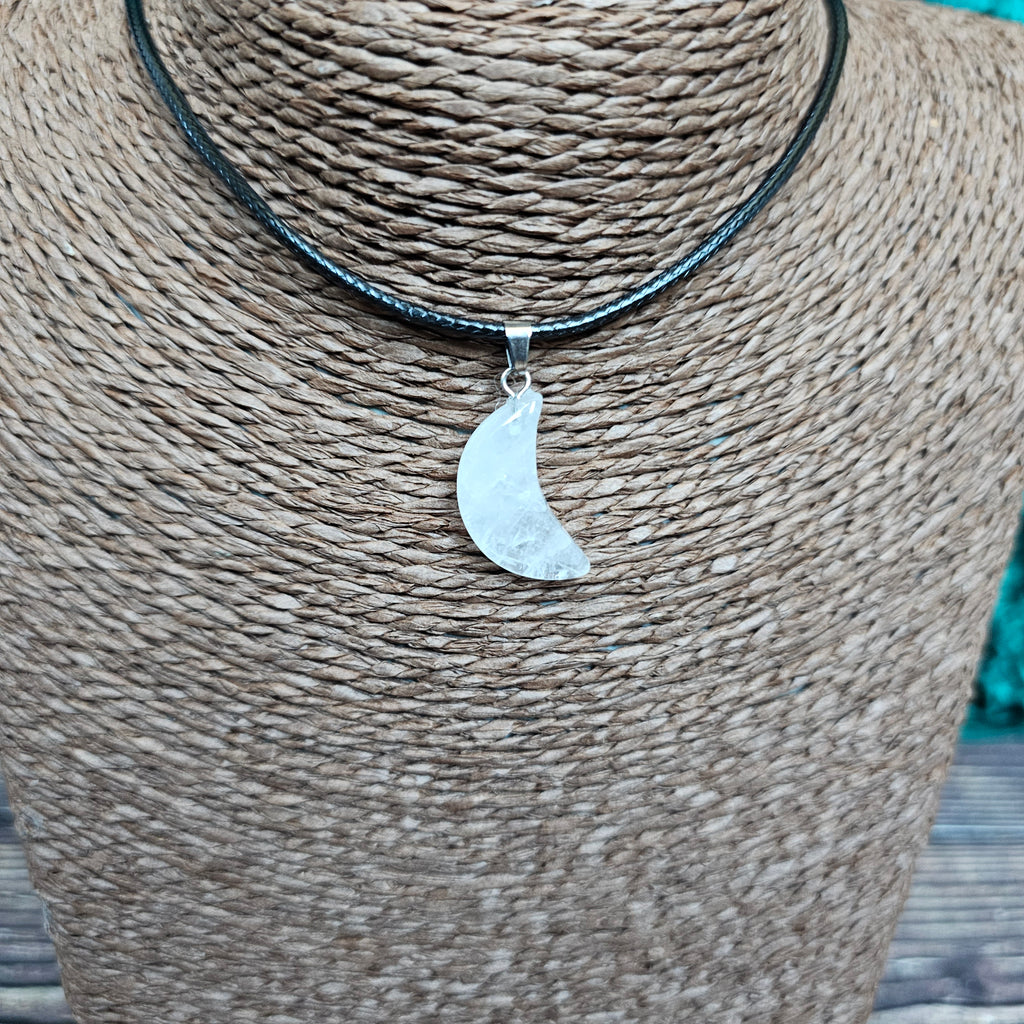 A crescent moon shaped crystal pendant on a black cord displayed on a mannequin 