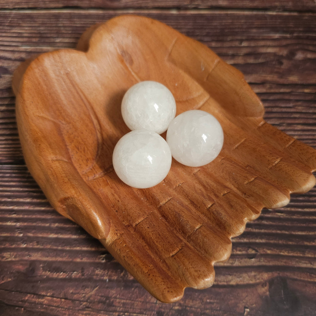 Three clear quartz spheres placed on a wooden surface.
