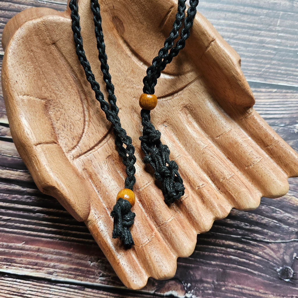 A black-coloured crystal cord necklace laid on a pair of wooden hands