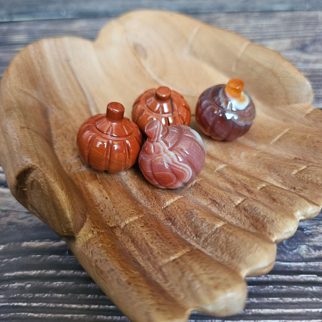 Four carved crystal pumpkins being held in a pair of wooden hands