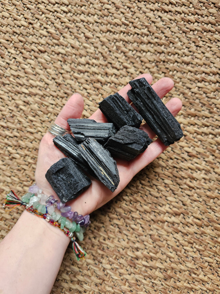 Hand holding black crystals on a textured brown surface